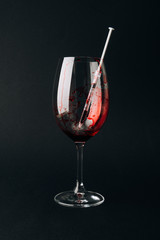 Wine glass with syringe and blood isolated on black