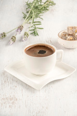 Cup of coffee served with Turkish delight on wooden table