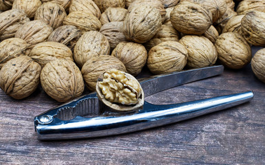  Walnuts with metal nutcracker on a wooden background