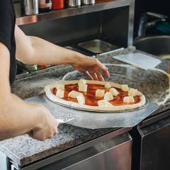 Cooking in modern pizza oven in cafe kitchen