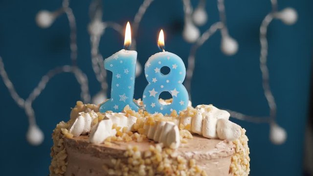 Birthday cake with 18 number candle on blue backgraund. Candles blow out. Slow motion and close-up view