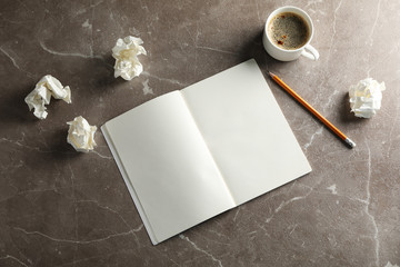 Blank notebook, paper balls, pencil and cup of coffee on grey background, top view
