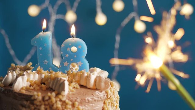 Birthday cake with 18 number candle and sparkler on blue backgraund. Slow motion and close-up view