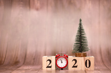 Alarm clock with Christmas decor tree and 2020 wooden blocks on table