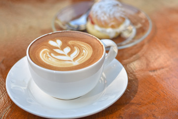 Cup of Latte coffee with cream on wooden background. Latte art added.
