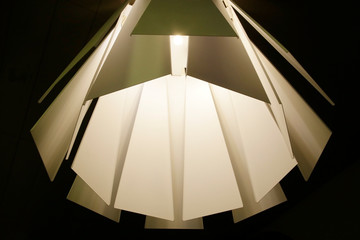 Metal panels of lamp or lampshade in retro style resembling structure or architectural surfaces. Abstract modern interior background with irregular geometric pattern of glowing elements.