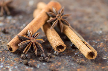 Cinnamon sticks, anise stars and black peppercorns on textured background
