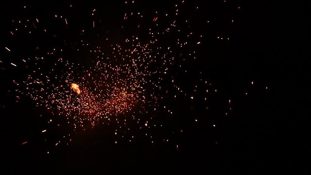 Bright firework exploding on the ground by night in front of a graffiti wall. Firework for kids. Slow motion