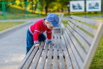 A child climbs on a park bench. Boy, summer.