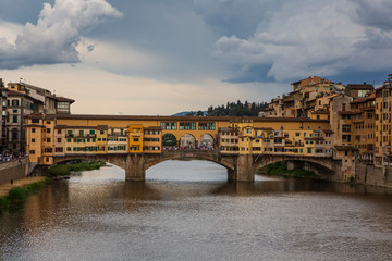 Obraz premium The Ponte Vecchio, a medieval stone closed-spandrel segmental arch bridge over the Arno River, in Florence, Italy, noted for still having shops built along it. 