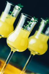 Limoncello with thyme in three grappas wineglass close up on dark background, shallow depth of the...