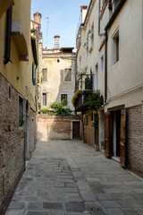 Narrow stone courtyard between the buildings. Sunny day, Venice, Italy.