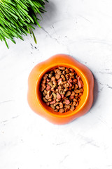 dry cat food in bowl on stone background top view