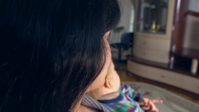 Pretty Mother With Remote Control in Hand and Cute Child Watching Personal Home Video. Sitting On Sofa Couch In Room. Slow Motion 30p 0.5 Real Time Speed