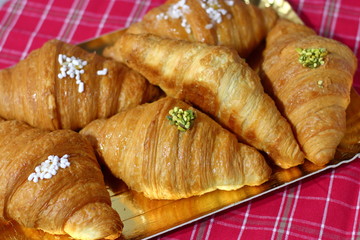 Fresh sweet buns on a golden tray and a red checkered tablecloth