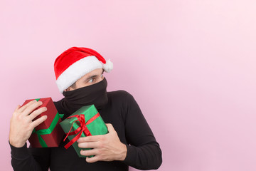 A thief in a red hat, stole someone else's Christmas gifts. Angry character, negative human emotions. Pink background, copy space.