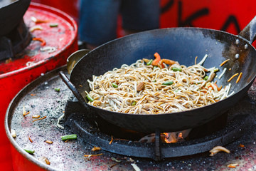 chef cooks Chinese noodle wok at street food festival