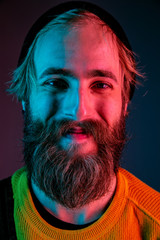 Smiling, close up. Caucasian man's portrait on gradient studio background in neon light. Beautiful male model with hipster style. Concept of human emotions, facial expression, sales, ad.