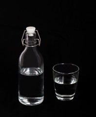 Clear bottle of water and a glass on black background