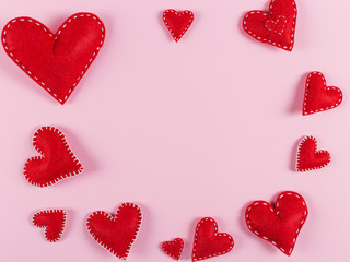 Red hearts are handmade on pink background. Preparation for Valentine's Day with a place for text. Copy space.