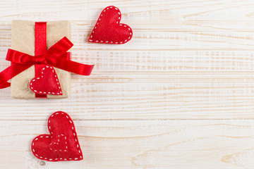 Preparation for Valentine's Day. Red hearts and craft gifts on white wooden background. Copy space.
