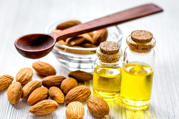 cosmetic and therapeutic almond oil on light wooden background