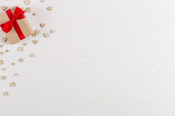Preparation for Valentine's Day. Red hearts and craft gifts on white wooden background. Copy space.