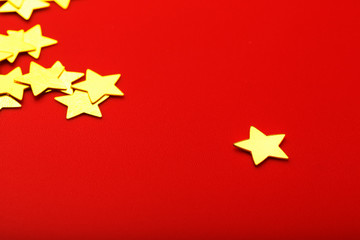 A scattering of Gold stars on a red background. Greeting cards, headlines and website concept.