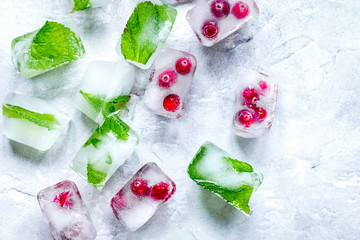 fresh cranberry in ice cubes on gray stone background top view