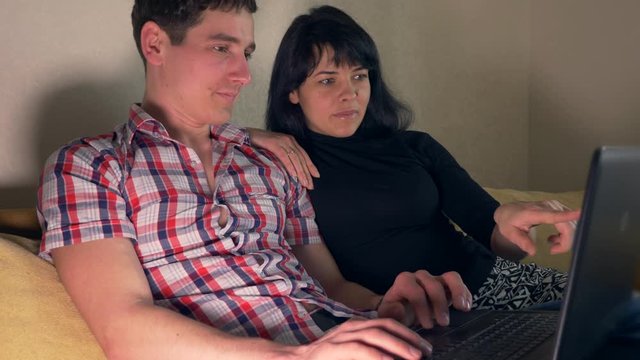 Family Couple Shopping Online. Woman Likes Shows Thumb Up Gesture. Woman Points Finger On Laptop Screen. Surfing Intrenet Sitting On Sofa Couch. Slow Motion 30p 0.5 Real Time Speed 60p