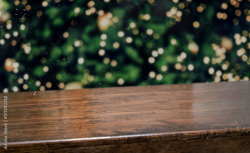 Wall mural wooden table top with abstract blur christmas tree with string light and snow fall background with b