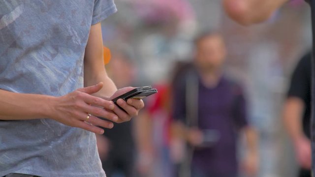Man in crowd searching information in mobile phone. Mobile technology. Mobile connection concept. Social network via mobile applications. Male tapping on sensor screen of smartphone on the street