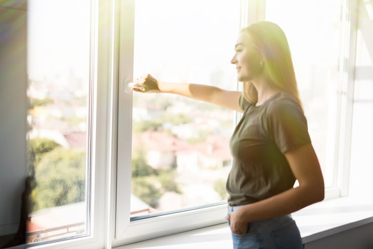 Happy woman open plastic windows for fresh air indoor