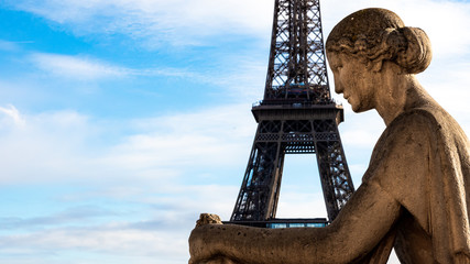 Fototapeta na wymiar The Eiffel Tower in Paris in the arms of a statue of a seated woman