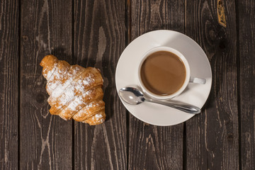 bun croissant with hot coffee with milk on a dark wooden background