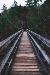 Moody empty bridge leading into a dark forest in Tallulah Falls Georgia