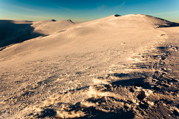 Landscape of mountain valley covered with snow on clear winter frosty day