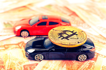 Bitcoin coin on the roof of black prestige car with blurred background of russian banknotes
