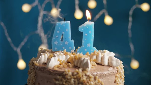 Birthday cake with 41 number candle on blue backgraund. Candles blow out. Slow motion and close-up view