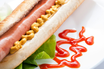 Hot dog with mustard and ketchup on white plate. Closeup of american hotdog.