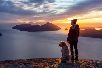 Adventurous Girl Hiking on top of a Mountain with a dog during a colorful sunset. Taken on Tunnel...