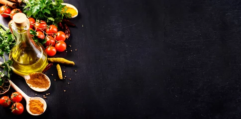 Foto auf Acrylglas Essen Lebensmittel Hintergrund. Draufsicht auf Olivenöl, Kirschtomate, Kräuter und Gewürze auf rustikalem schwarzem Schiefer. Bunte Lebensmittelzutatengrenze.