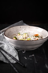 Asian beef salad with cucumber, noodles and rice flakes. Thai dish on black wooden background.