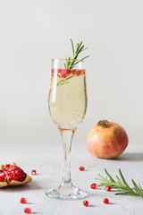 Pomegranate Christmas cocktail with rosemary, sparkling wine on white. Xmas Holiday drink.