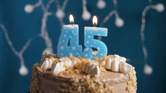 Birthday cake with 45 number candle on blue backgraund. Candles blow out. Slow motion and close-up view