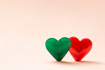 Two green and red hearts on a clear and clean pink background. Concept of love and company. Valentine's day