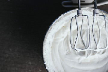  Beating a white cream with a mixer in a metal bowl. Whipped cream. Cream for the cake.