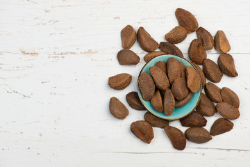 Brazil nuts in a turquoise bowl on a white shabby background