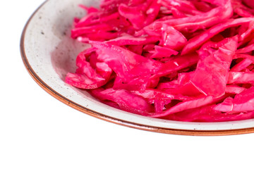 Tasty red sauerkraut or fermented cabbage in marinade on a plate isolated on white.