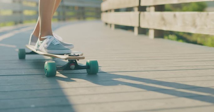 Close up shot of a skater girl's feet riding on a longboard, skateboarding carving style in slow motion, surf skate lifestyle concept